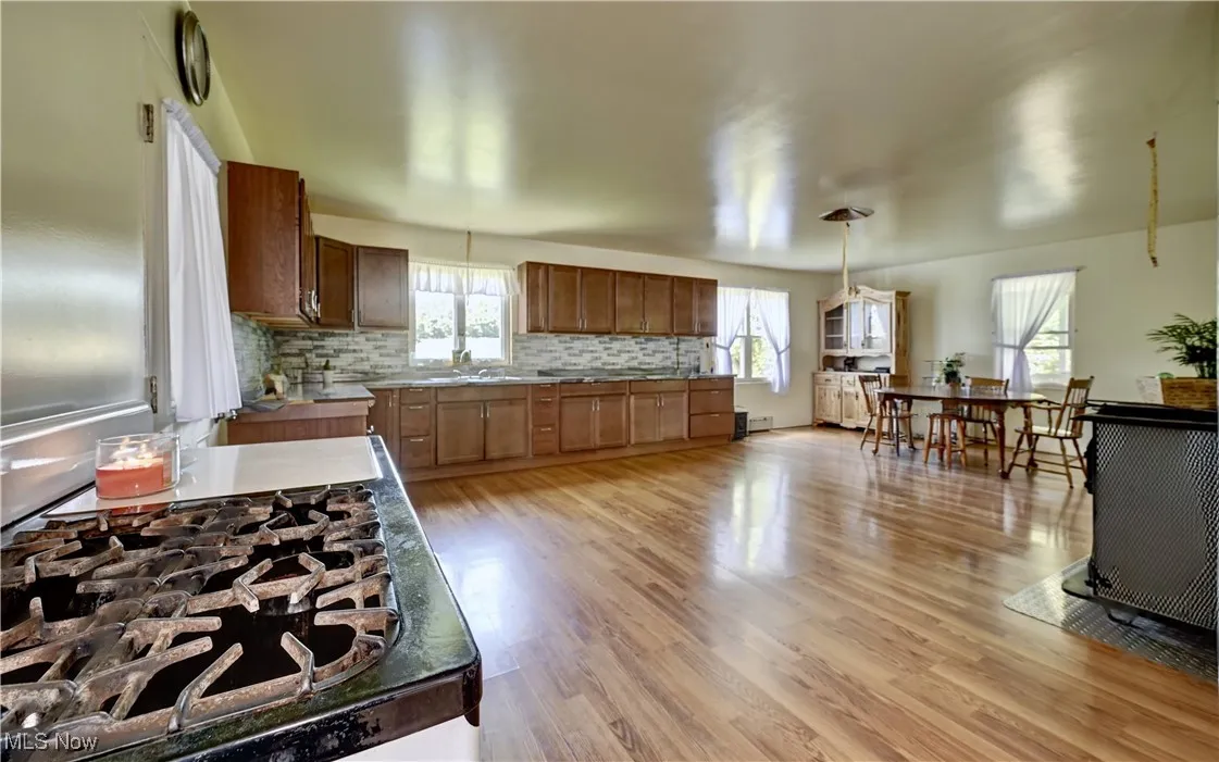 Kitchen featuring decorative backsplash,light wood-style flooring, brown cabinets, and plenty of natural light