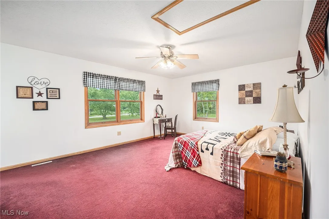 Carpeted bedroom featuring ceiling fan and baseboards