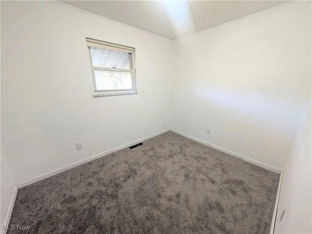 Carpeted empty room featuring baseboards