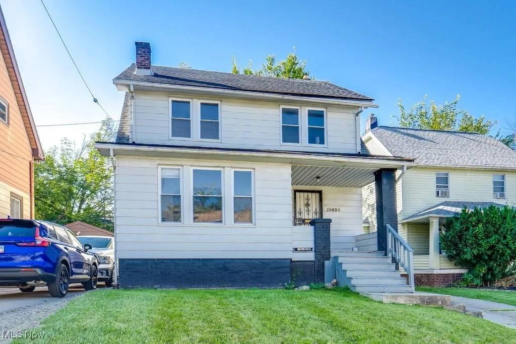 American foursquare style home featuring a chimney, a porch, and a front lawn
