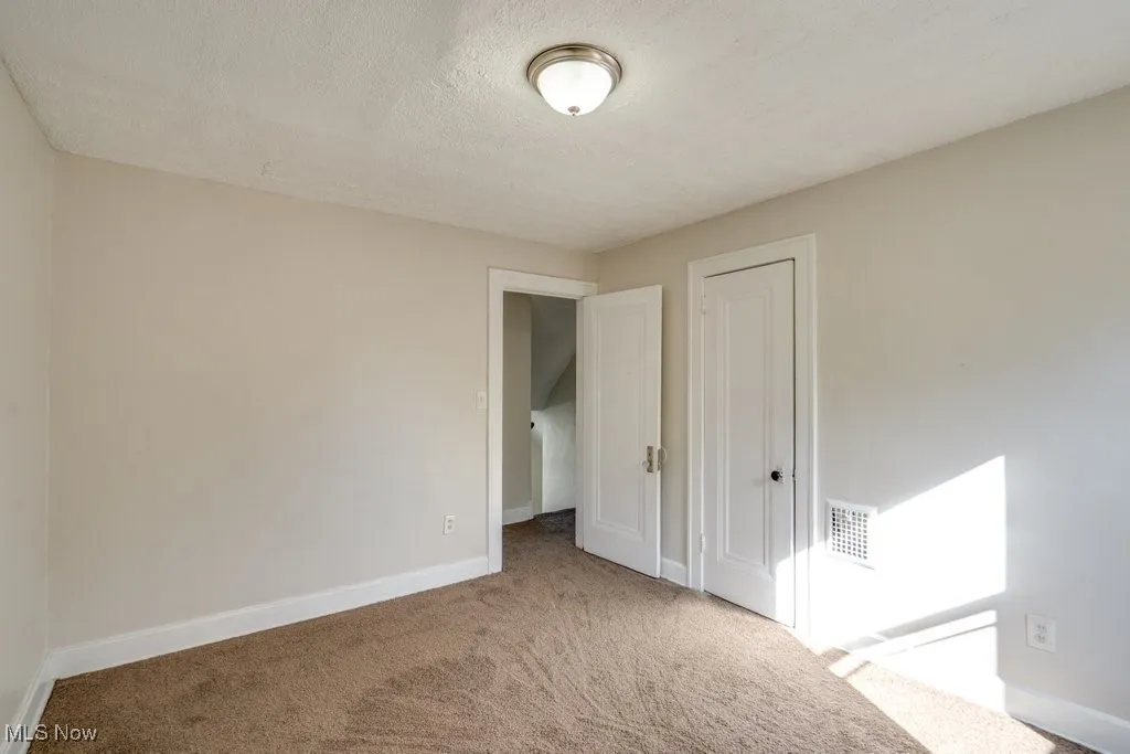 Unfurnished bedroom featuring a textured ceiling, carpet, and a closet