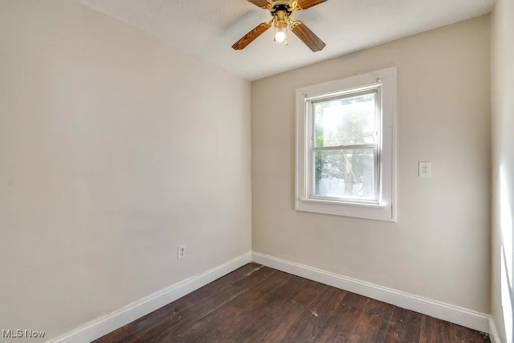 Unfurnished room featuring dark wood-style floors and a ceiling fan