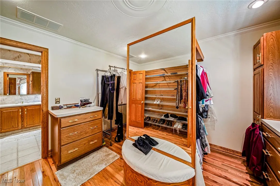 Bedroom featuring crown molding, light wood-style flooring, a closet, and a textured ceiling