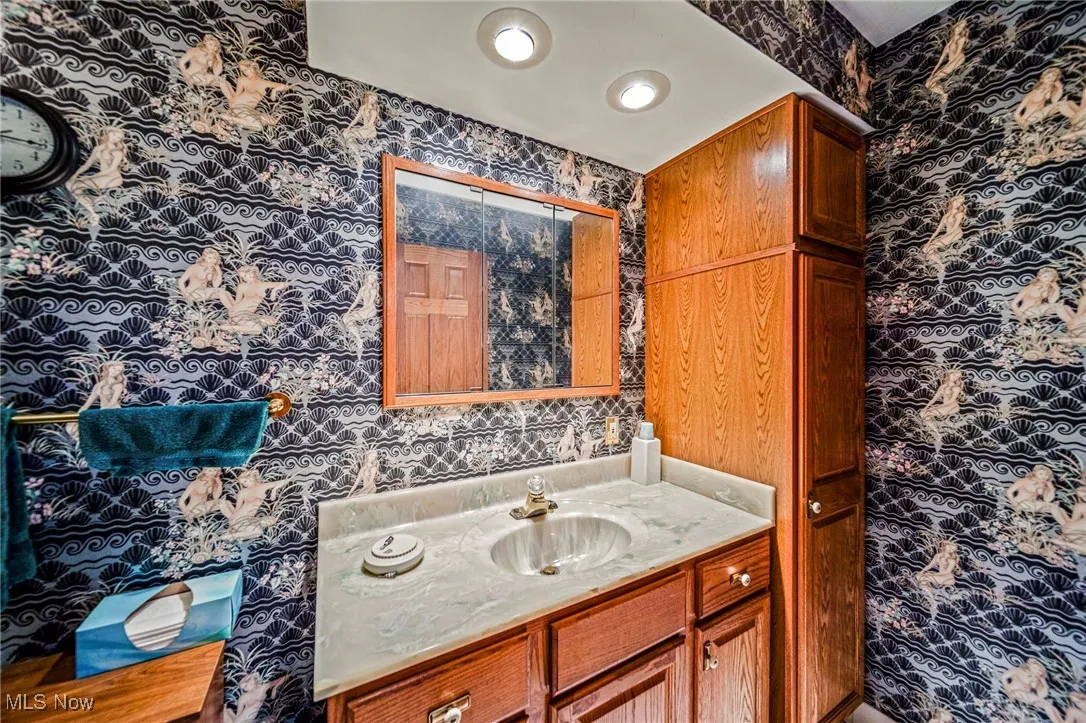Bathroom with wallpapered walls and vanity