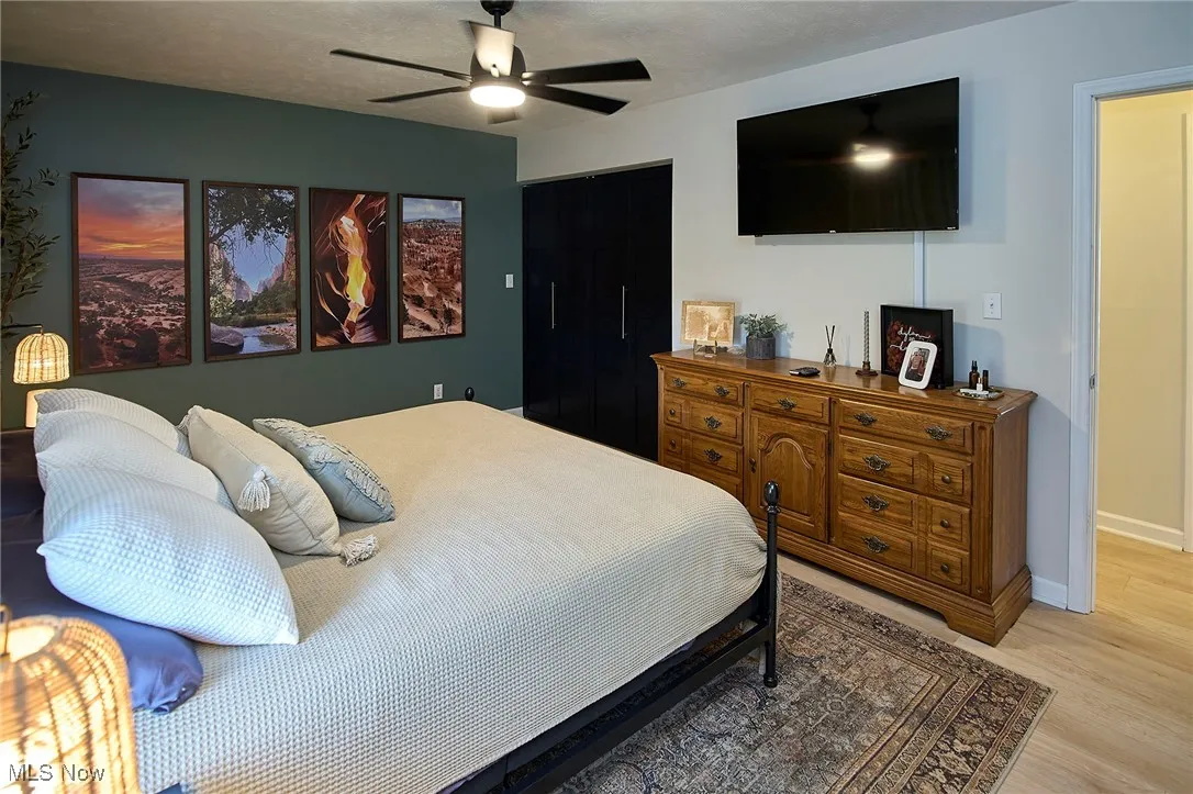Bedroom with light wood-style floors, ceiling fan, a textured ceiling, and a closet