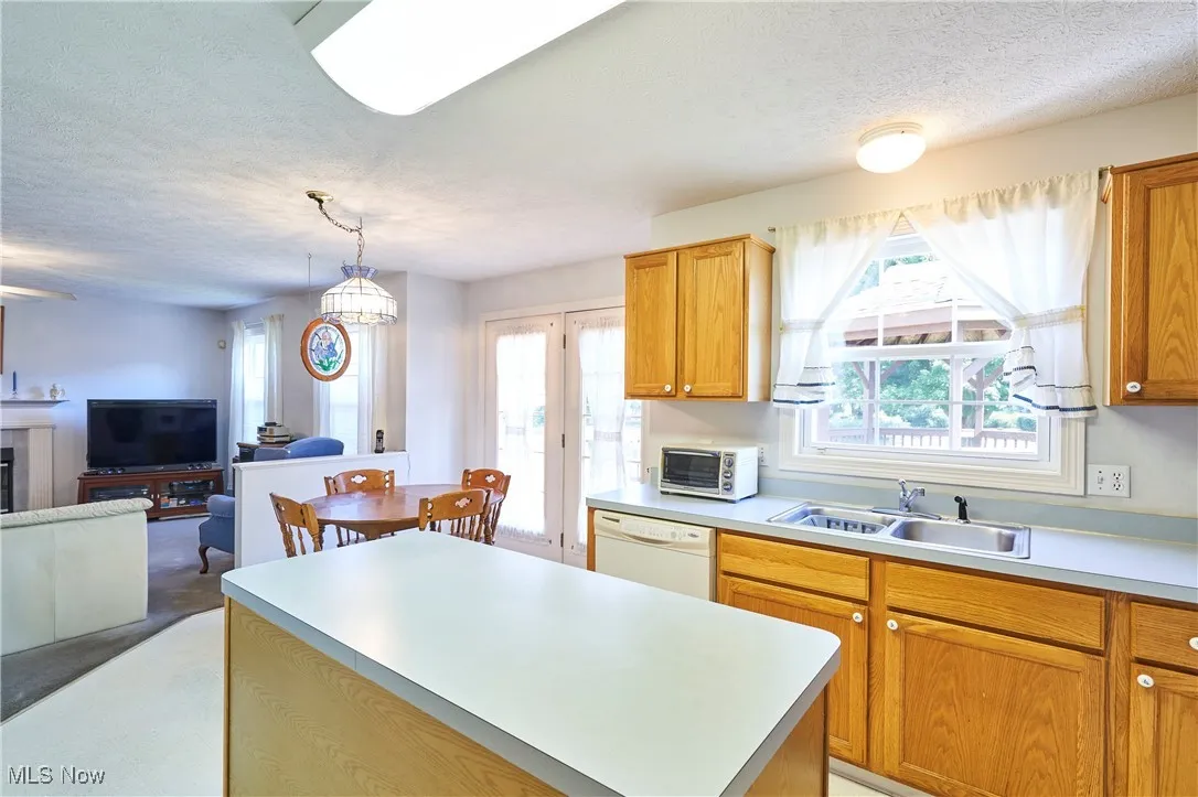 Kitchen with a textured ceiling, a center island, light countertops, hanging light fixtures, and open floor plan