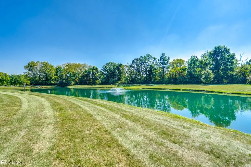 View of property's community with a water view and a lawn
