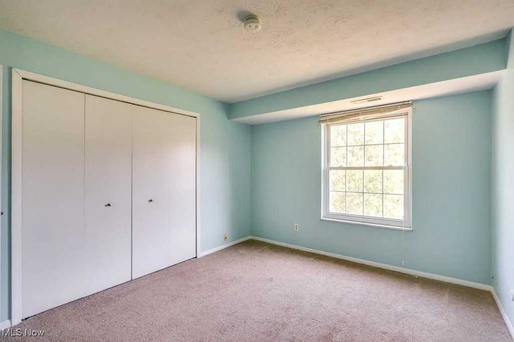 Unfurnished bedroom with carpet, a textured ceiling, and a closet