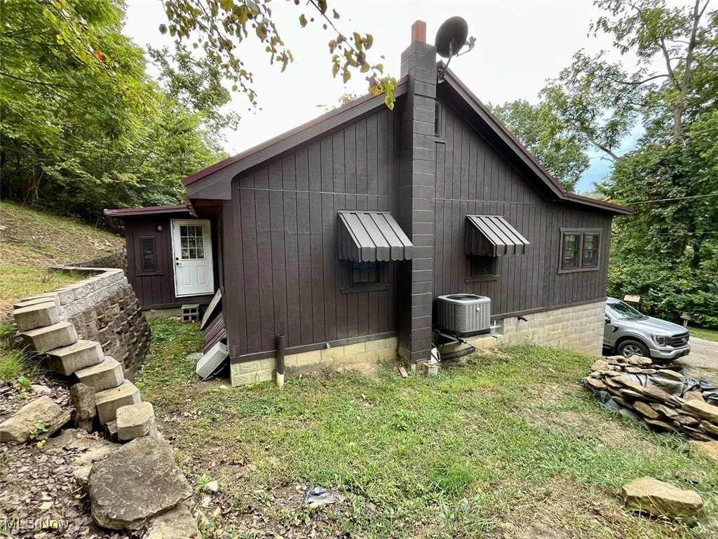 View of property exterior with a central AC unit and a chimney