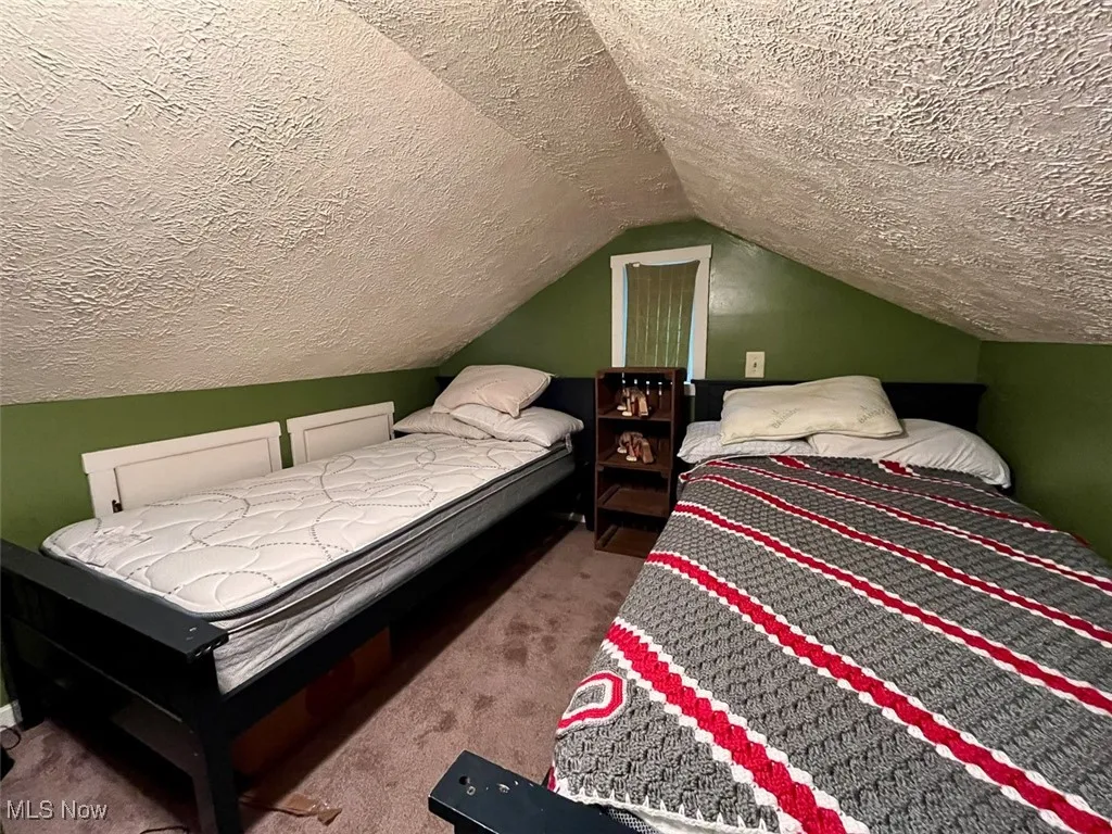 Bedroom with carpet flooring, a textured ceiling, and vaulted ceiling