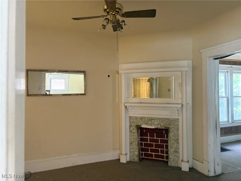 Unfurnished living room with carpet, a high end fireplace, and a ceiling fan