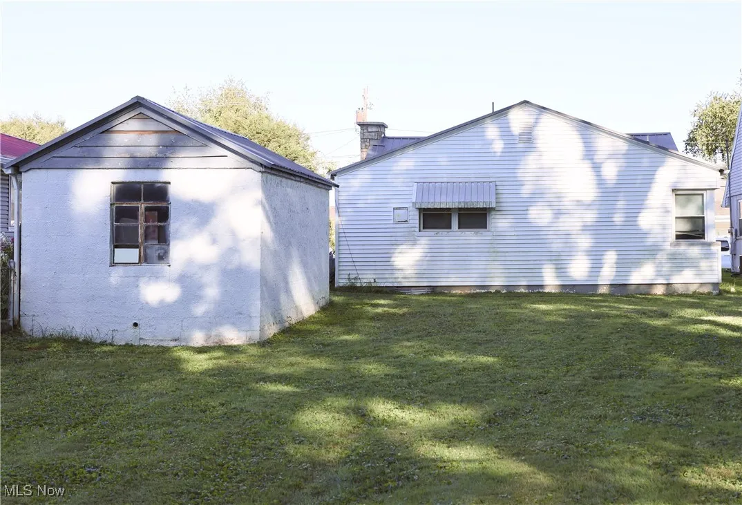 Back of property featuring a lawn and an outdoor structure