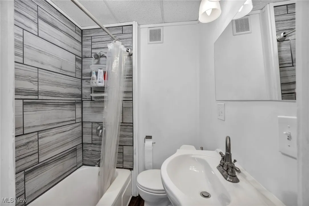 Bathroom with shower / bath combination with curtain and a paneled ceiling