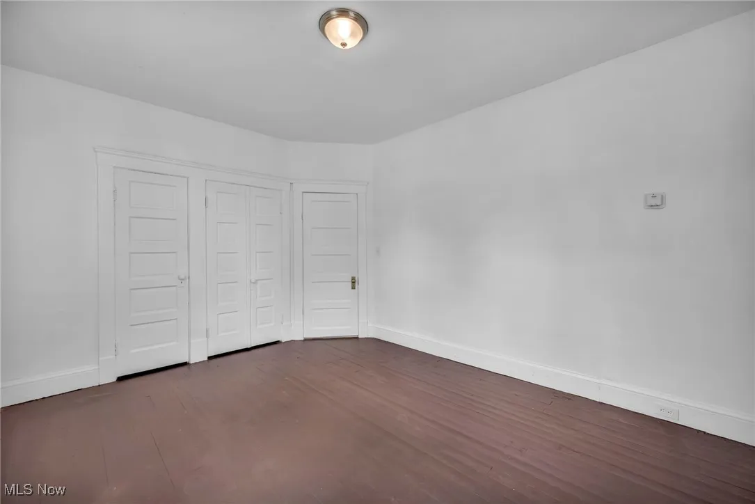 Unfurnished bedroom with dark wood-style floors and a closet