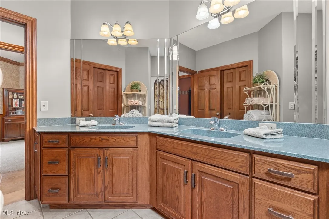 Bathroom with double vanity, light tile patterned floors, and a closet
