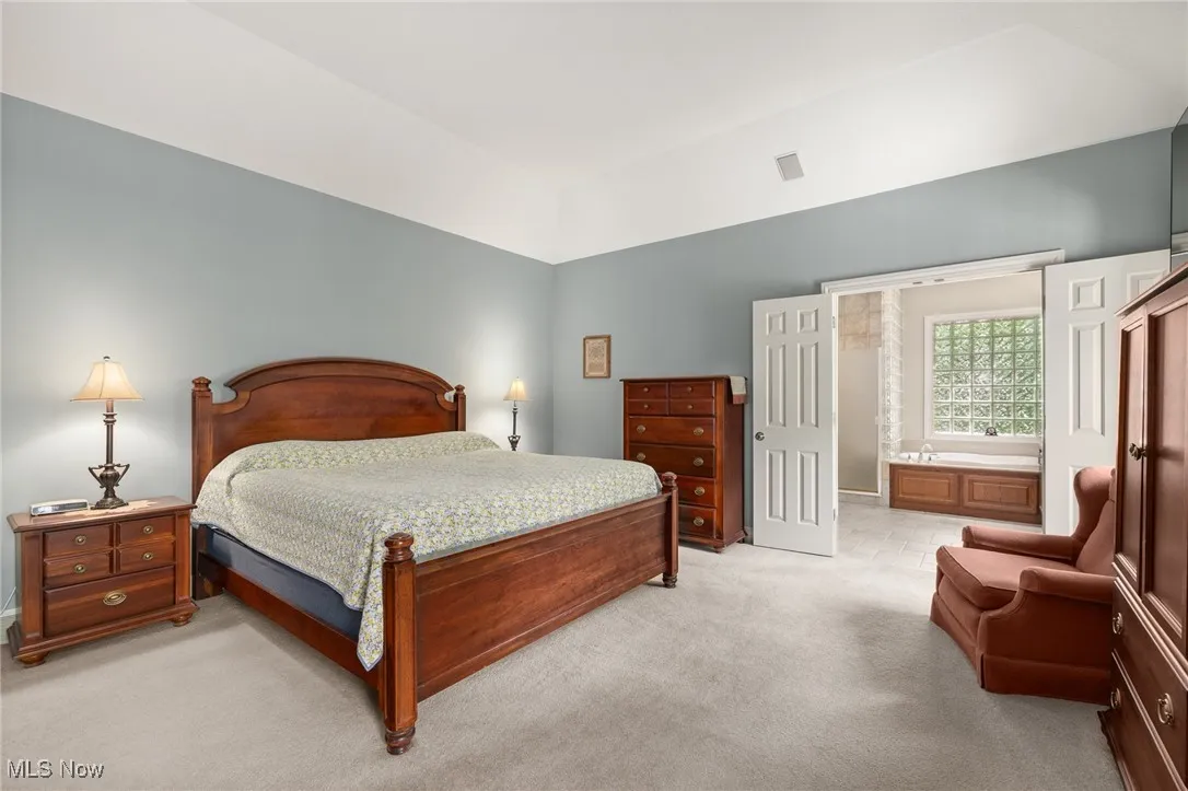 Bedroom featuring light carpet and ensuite bathroom