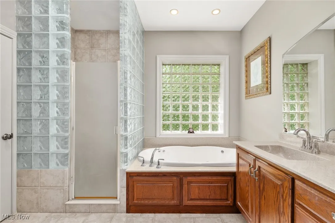Full bath with vanity, a stall shower, a garden tub, light tile patterned floors, and recessed lighting