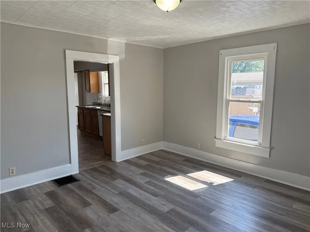 Empty room with dark wood-style floors and ornamental molding