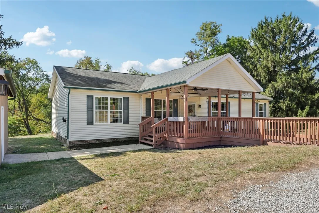 View of front of property featuring ceiling fan, a front yard, a wooden deck, and a shingled roof