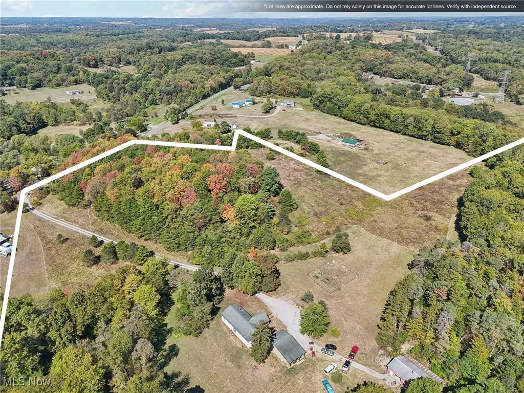 Aerial view of property and surrounding area with a heavily wooded area and property parcel outlined