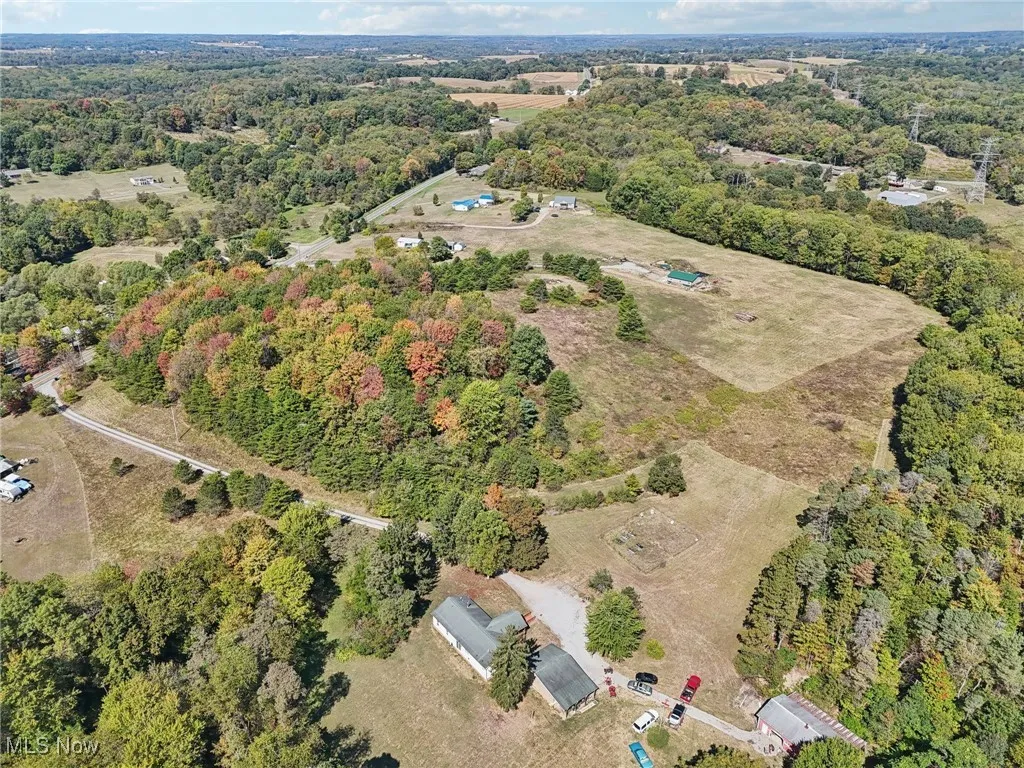 Aerial view of property and surrounding area with a heavily wooded area