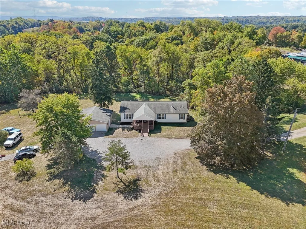Aerial view of property and surrounding area featuring a heavily wooded area