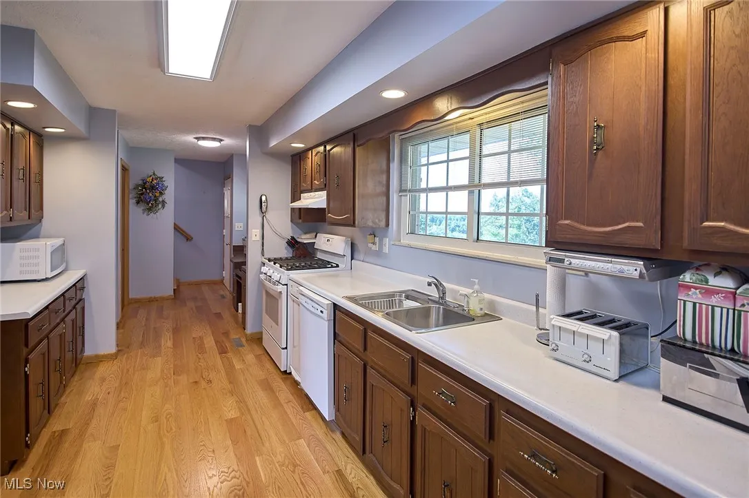 Kitchen with white appliances, light countertops, light wood-style flooring, and recessed lighting