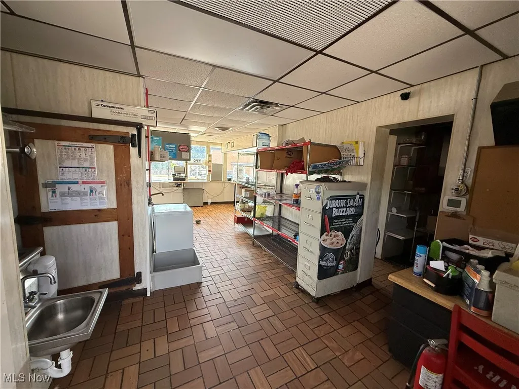 Kitchen featuring a drop ceiling, brick patterned flooring, and wood walls