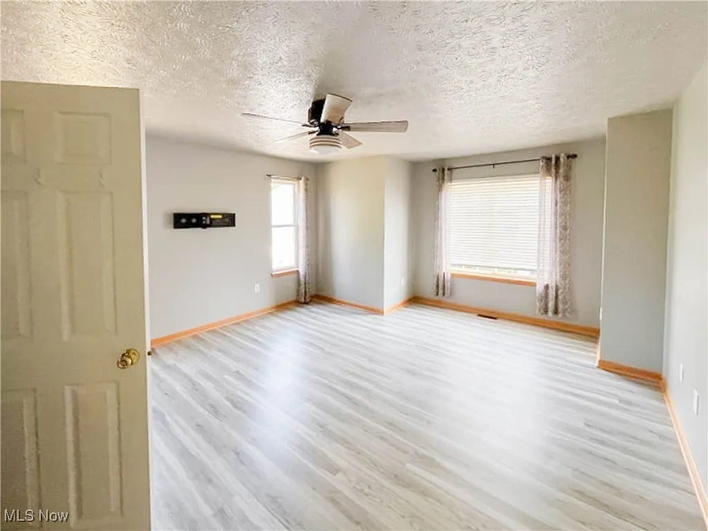 Bedroom featuring light wood-type laminate flooring, a textured ceiling, and ceiling fan