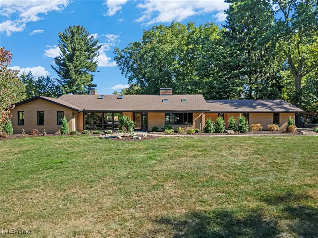 Ranch-style house featuring a chimney, a front yard, and brick siding