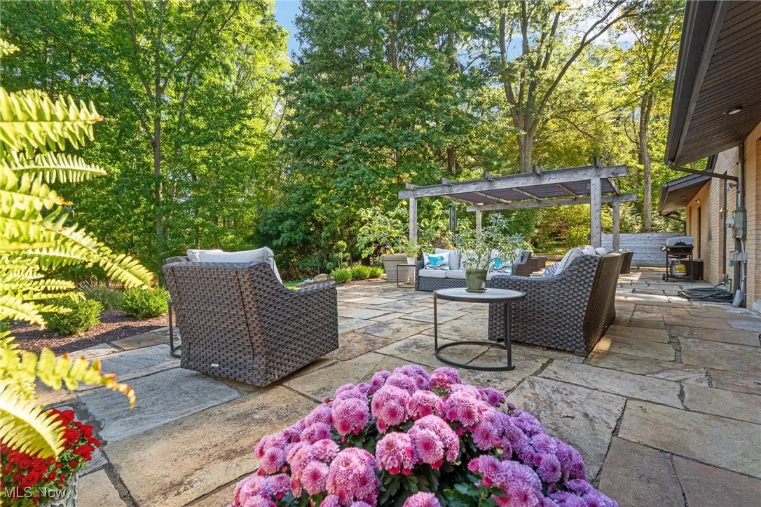 View of patio featuring outdoor lounge area, a pergola, view of wooded area, and area for grilling