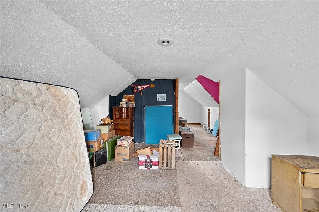 Additional living space featuring a textured ceiling, lofted ceiling, and carpet