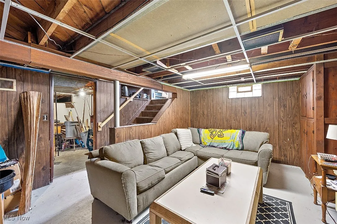 Living room with wooden walls, concrete floors, and stairs