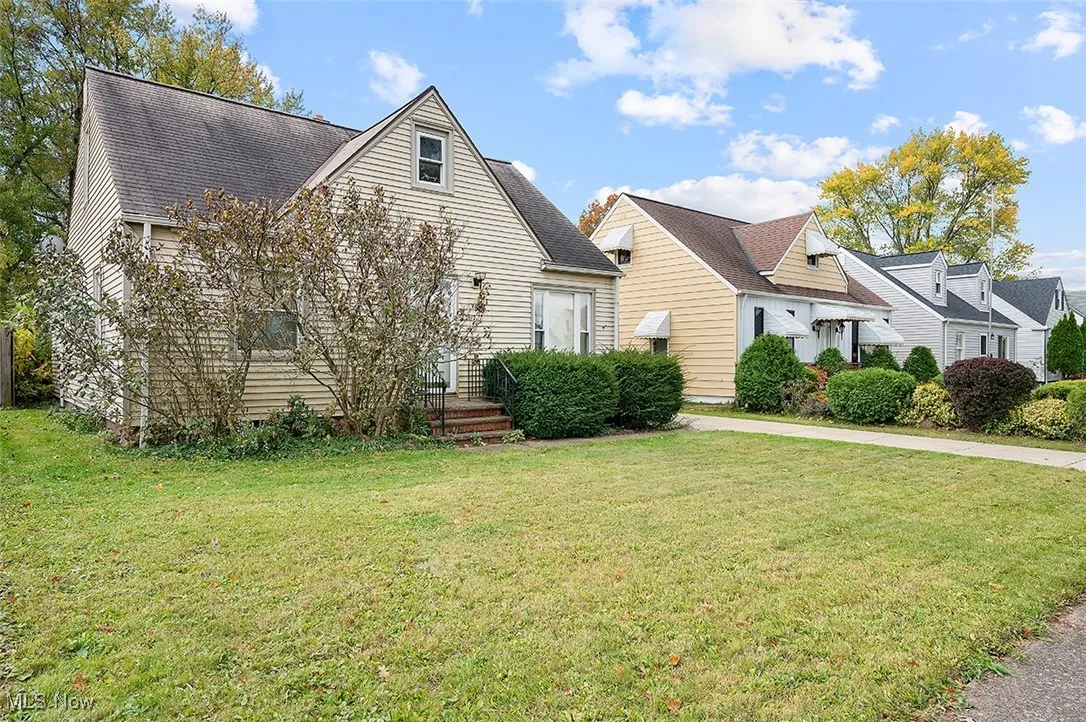 View of front facade with a front yard and a shingled roof