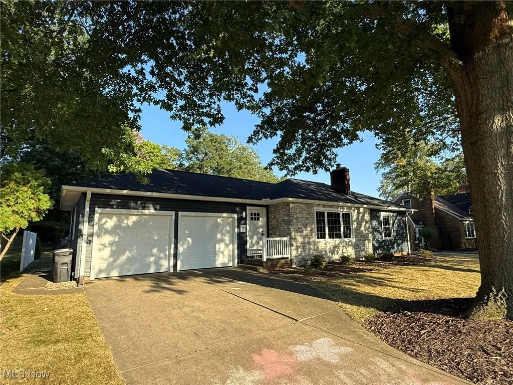 Single story home with driveway, a chimney, a garage, and a front lawn