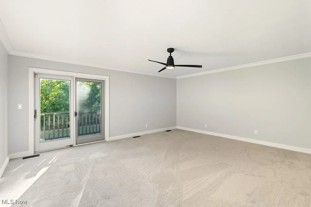 Empty room with crown molding, light carpet, and a ceiling fan