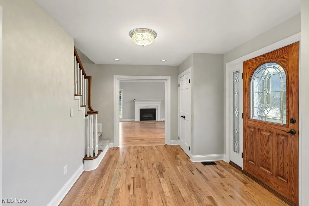 Foyer featuring light wood-style flooring, a fireplace, stairway, and recessed lighting