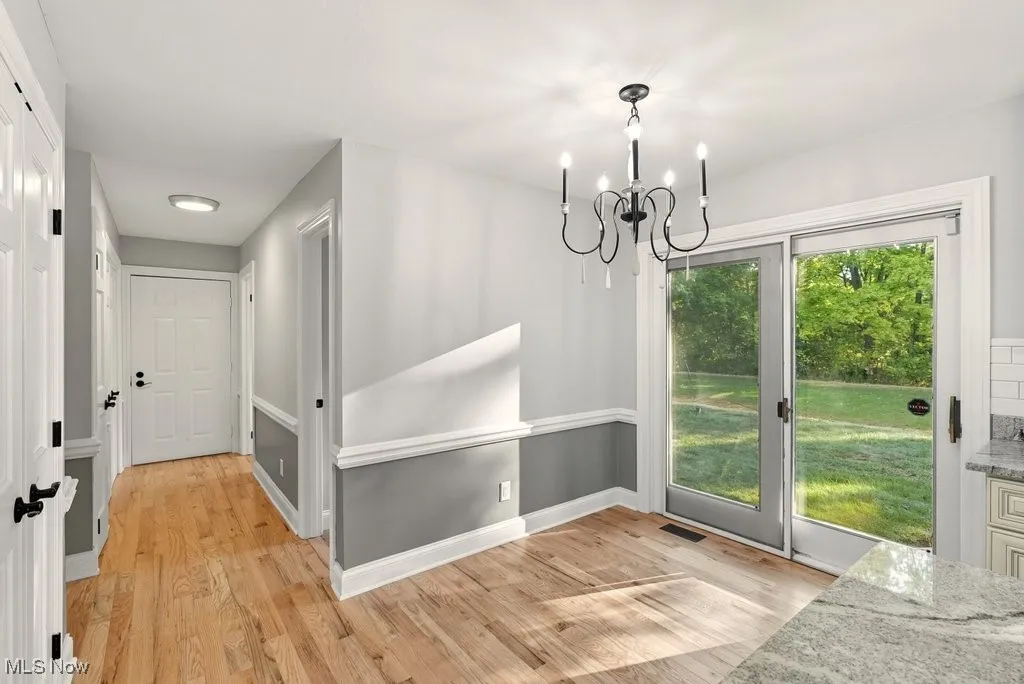 Doorway to outside with wood finished floors and a chandelier