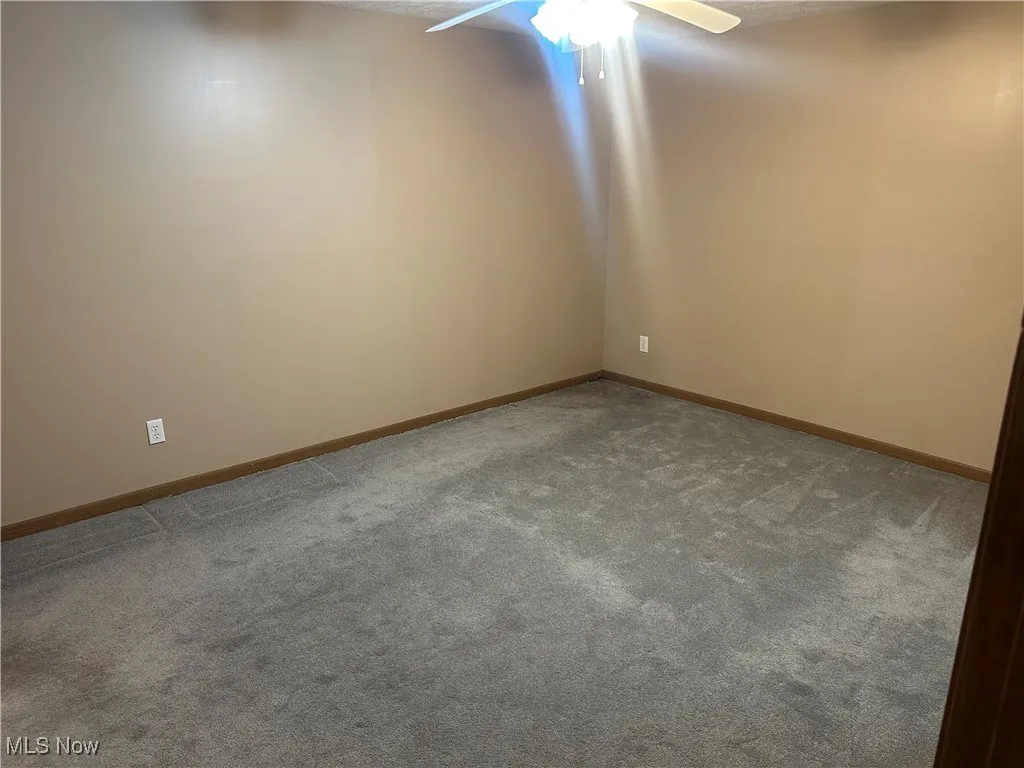 Empty room featuring carpet, a textured ceiling, and ceiling fan