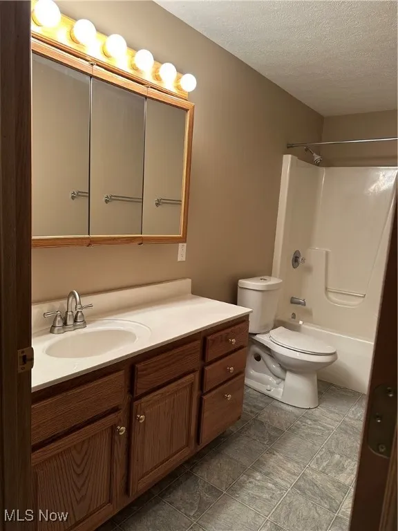 Full bath featuring a textured ceiling, vanity, and shower / bathtub combination