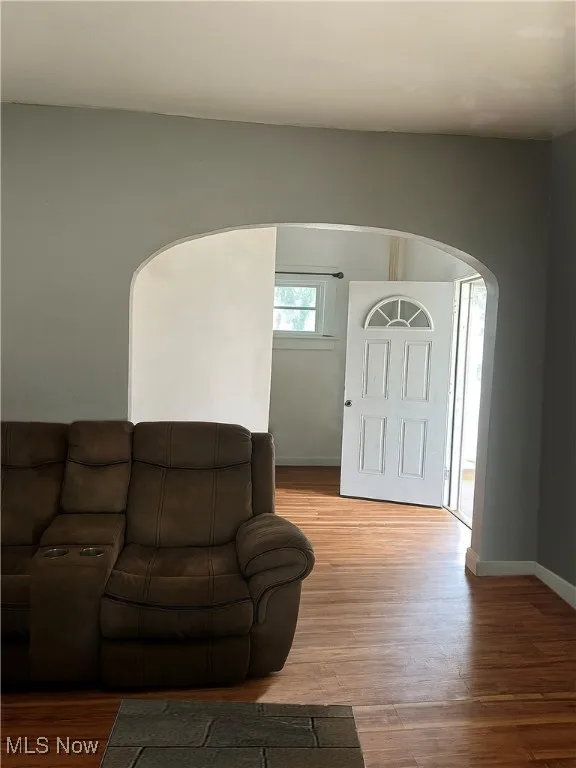 Living room with arched walkways and wood finished floors