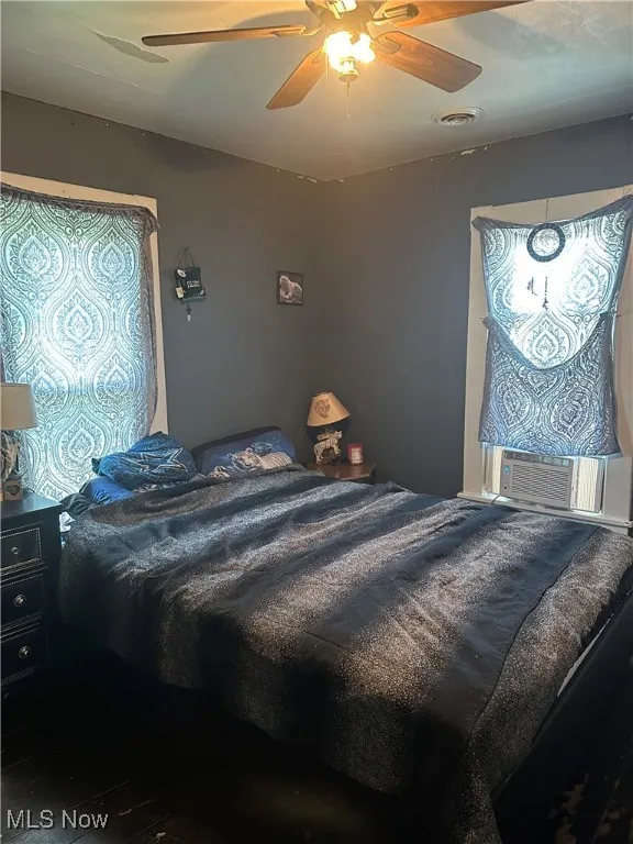 Bedroom with a ceiling fan, wood finished floors, and cooling unit