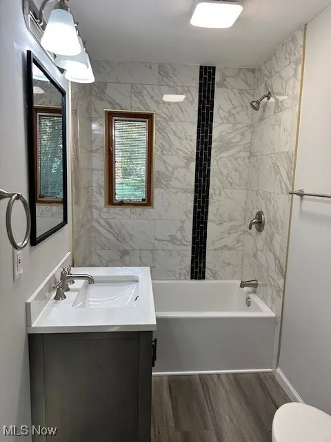 Full bathroom with  shower combination, vanity, and dark wood-style floors
