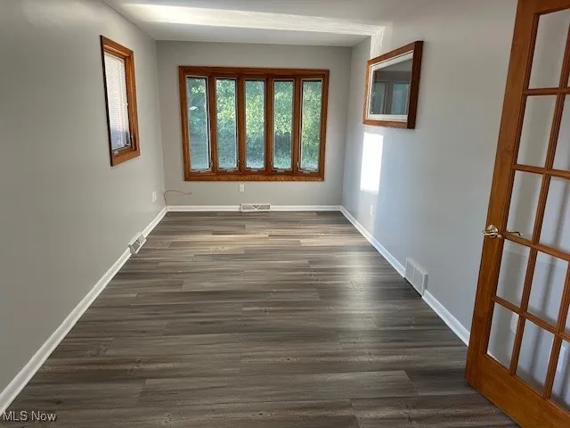 Unfurnished room with healthy amount of natural light and dark wood-style flooring