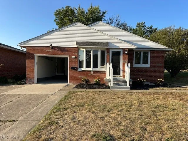 View of front facade featuring a garage, brick siding, concrete driveway, and a front lawn
