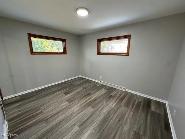 Spare room featuring wood finished floors, healthy amount of natural light, and baseboard heating