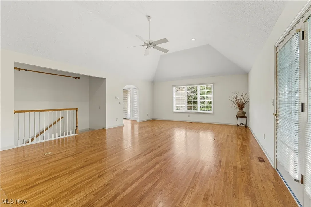Unfurnished bedroom with light wood-style floors, ceiling fan, access to outside, and high vaulted ceiling