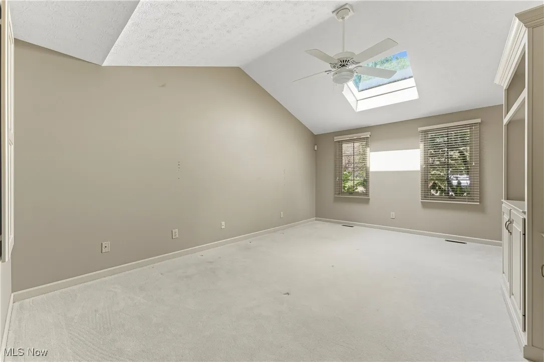 Bonus room featuring a skylight, vaulted ceiling, carpet, ceiling fan, and a textured ceiling