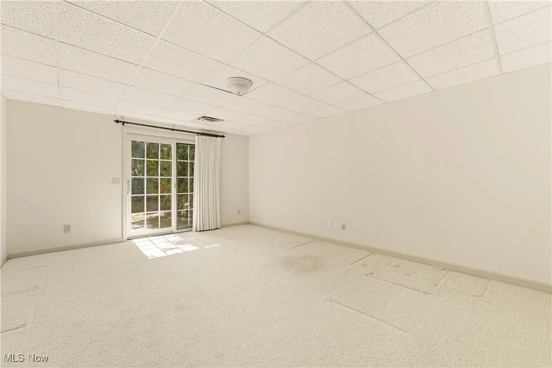 Empty room featuring a paneled ceiling and carpet flooring