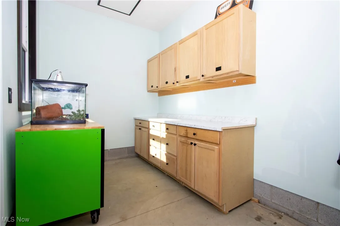 Kitchen with light brown cabinets, light countertops, and concrete floors